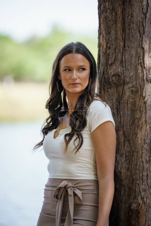 Téléchargez les photos : Photo d'un beau modèle féminin posant par arbre dans la nature - en image libre de droit
