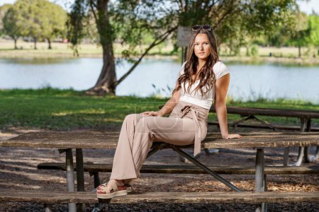Foto de Foto de una joven modelo sentada en un banco del parque mirando lejos de la cámara - Imagen libre de derechos