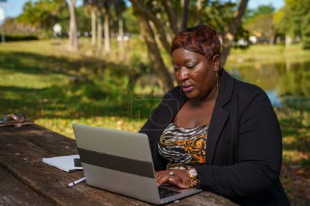 Foto de CEO empresaria escribiendo en su computadora portátil mientras trabaja a distancia del parque - Imagen libre de derechos