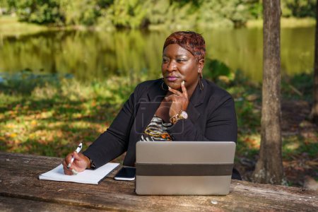 Téléchargez les photos : Belle femme d'affaires afro-américaine travaillant dans le parc - en image libre de droit