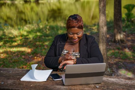 Photo for Businesswoman checking the time on her watch to join an online meeting while in a park - Royalty Free Image