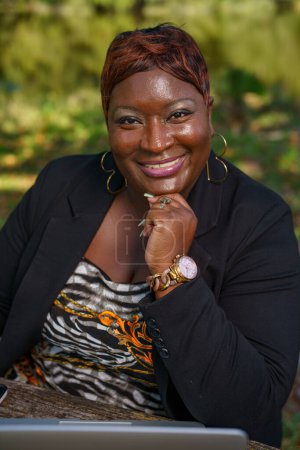 Téléchargez les photos : Belle femme d'affaires afro-américaine travaillant dans le parc - en image libre de droit