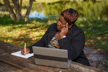 Photo for Woman in business teleworking in the park with laptop computer - Royalty Free Image