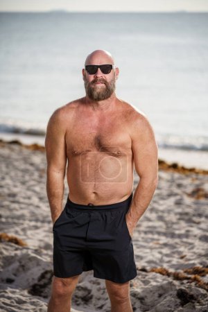 Téléchargez les photos : Homme dur avec barbe sur la plage - en image libre de droit