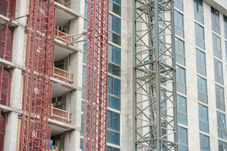 Téléchargez les photos : Photo de l'ascenseur et de la section de la grue attachés à un bâtiment en construction - en image libre de droit