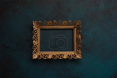 Téléchargez les photos : Cadre en métal bronze ajouré vintage sur un fond mural bleu, maquette de cadre photo vide - en image libre de droit