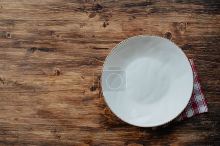 Foto de Fondo de la cena, plato vacío y servilleta en mesa rústica de madera, vista superior con lugar para el texto - Imagen libre de derechos