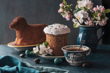 Oster-Tischdekoration mit Osterkuchen in Lammform, Frühlingsblumen, Eiern und einer Tasse Kaffee