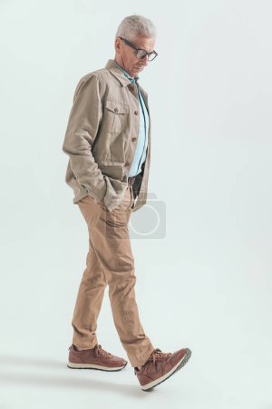 Foto de Mayor hombre casual en sus sesenta años es caminar con las manos en los bolsillos y mirando hacia abajo se siente triste - Imagen libre de derechos