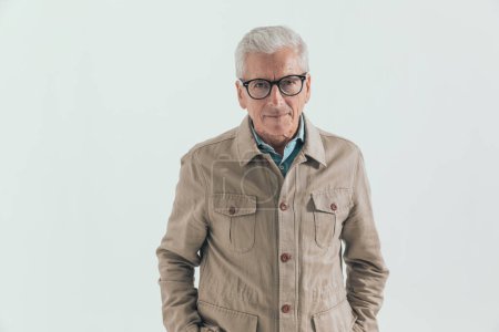 Foto de Viejo hombre casual posando con las manos en los bolsillos, usando anteojos y sintiéndose relajado - Imagen libre de derechos