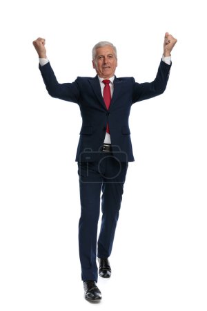 Téléchargez les photos : Full body picture of an happy businessman walking towards the camera and celebrating success - en image libre de droit