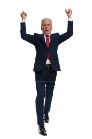 Téléchargez les photos : Full body picture of an excited old businessman walking to the camera and celebrating the Victory - en image libre de droit