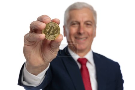 Photo for Old businessman presenting a bitcoin at the camera encouraging us to invest in crypto coins - Royalty Free Image