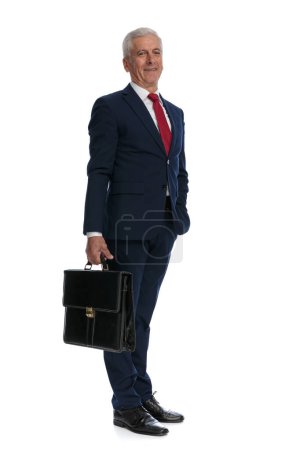 Foto de Full body picture and Side view of an old business man holding a briefcase and putting one hand in pocket - Imagen libre de derechos