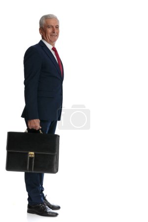 Photo for Full body picture and side view of an old businessman waiting in line with his briefcase in hand - Royalty Free Image