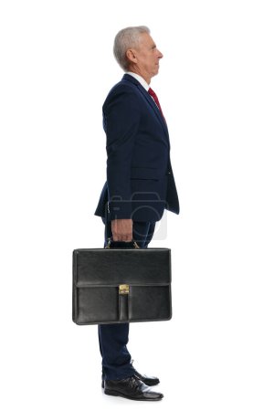 Téléchargez les photos : Full body picture and side view of an Old businessman feeling irritated to wait in line and hold his Briefcase - en image libre de droit