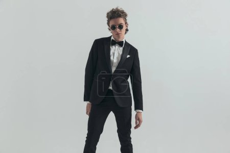 Photo for Portrait of sexy caucasian man with curly hair wearing elegant tuxedo and posing in front of grey background in studio - Royalty Free Image