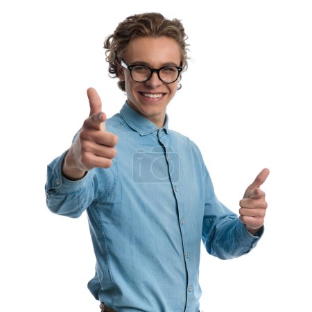 Photo for Portrait of handsome casual man pointing at the camera and smiling, standing, wearing eyeglasses against white studio background - Royalty Free Image