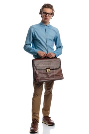 Photo for Full body picture of young casual man holding briefcase and posing, standing, wearing eyeglasses against white studio background - Royalty Free Image