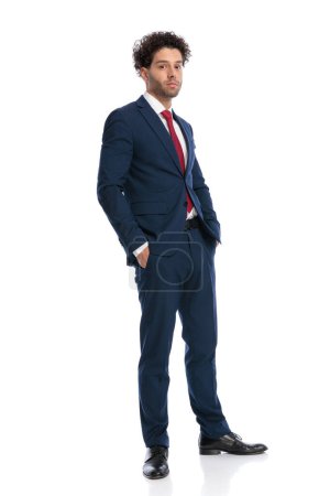 Photo for Full length picture of sexy arabic man in elegant suit posing with hands in pockets in front of white background in studio - Royalty Free Image