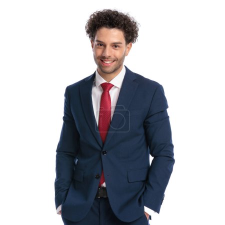 Photo for Handsome young man in elegant suit smiling and posing with hands in pockets in front of white background in studio - Royalty Free Image