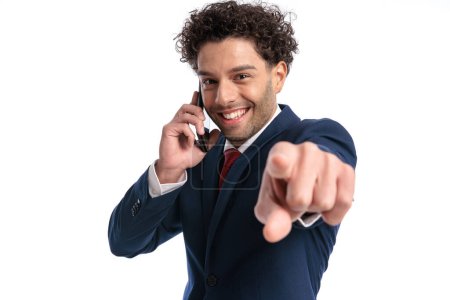 Foto de Happy elegant man talking on the phone, smiling and pointing finger in front of white background in studio - Imagen libre de derechos