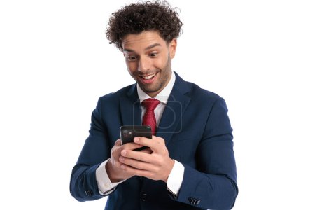 Téléchargez les photos : Excité jeune homme d'affaires lisant des messages et étant enthousiaste devant fond blanc en studio - en image libre de droit