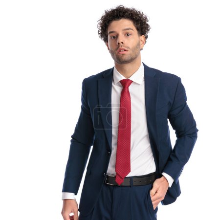 Photo for Sexy arabic businessman with curly hair holding hands in pockets and posing in front of white background in studio - Royalty Free Image
