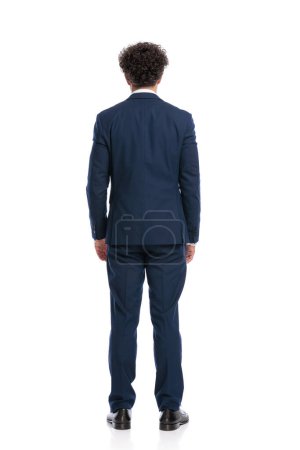 Téléchargez les photos : Behind view of elegant young man in suit standing in front of white background in studio - en image libre de droit
