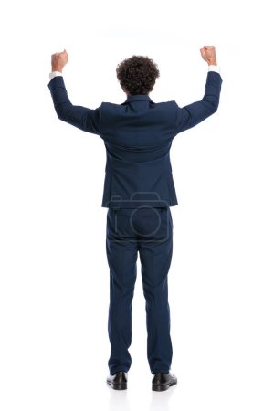 Téléchargez les photos : Excited young businessman holding fists in the air and celebrating in front of white background in studio - en image libre de droit