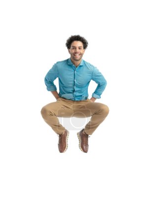 Photo for Happy greek with curly hair jumping up in the air and smiling in front of white background in studio - Royalty Free Image