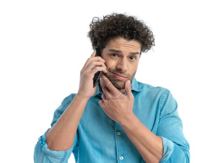 Téléchargez les photos : Portrait of pensive man having a phone conversation and thinking while holding hand to chin on white background - en image libre de droit