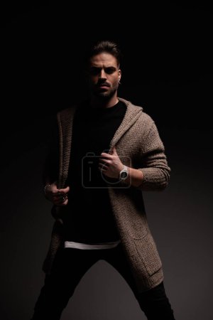 Foto de Portrait of handsome casual man arranging his coat with tough attitude, standing, in a fashion pose - Imagen libre de derechos