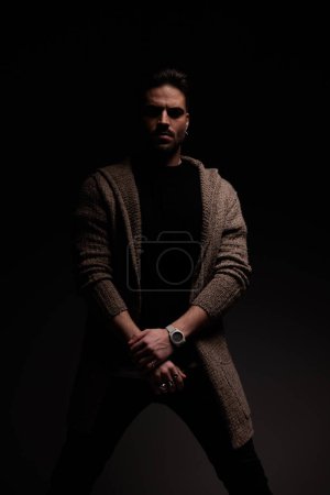 Portrait of young guy holding hand with a sexy stance, standing, in a fashion pose