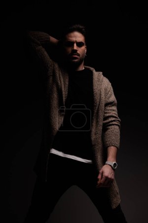 Foto de Portrait of sexy male model holding one hand behind head with masculine frame, standing, in a fashion pose - Imagen libre de derechos