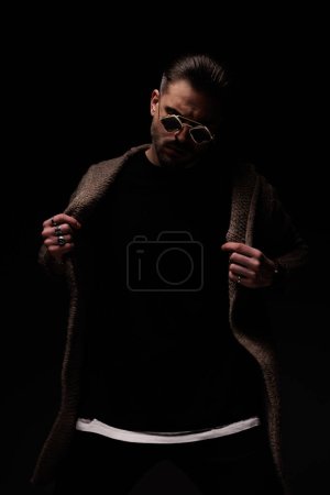 Téléchargez les photos : Portrait of sexy guy arranging his wool coat with style, standing, in a fashion pose - en image libre de droit