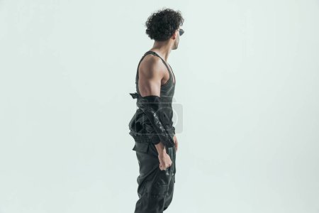 Téléchargez les photos : Attractive casual man taking jacket off and looking away, wearing a leather costume in a fashion pose - en image libre de droit