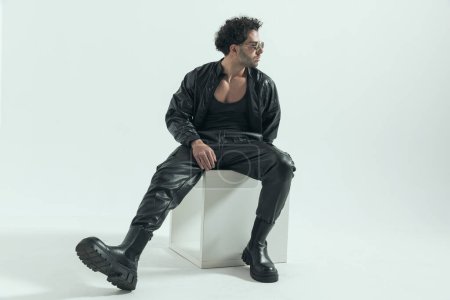Photo for Handsome casual man looking to his side, wearing a leather costume in a fashion pose - Royalty Free Image