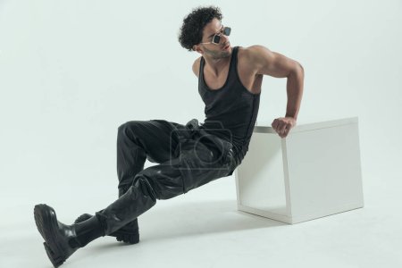 Photo for Young casual man doing some dips at the chair, wearing a leather costume in a fashion pose - Royalty Free Image