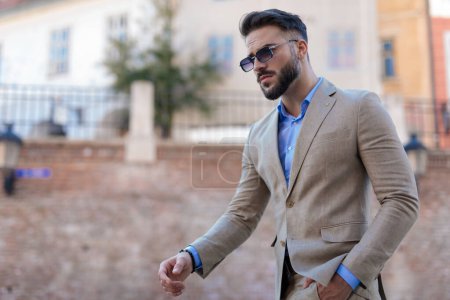 Photo for Portrait of sexy young businessman in suit with blue shirt and glasses looking away and walking outdoor in a city from Transylvania - Royalty Free Image