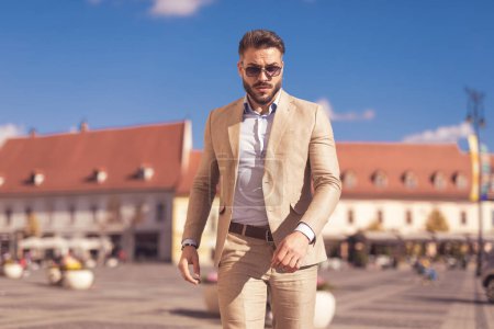 Photo for Portrait of attractive businessman posing with tough vibe, wearing sunglasses outdoor, in the old medieval town - Royalty Free Image