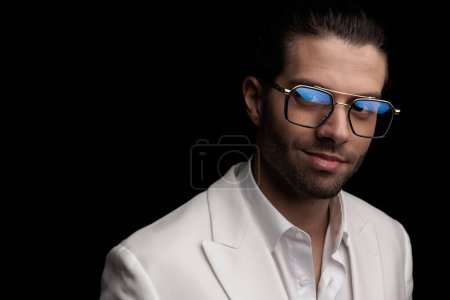 Téléchargez les photos : Image rapprochée de l'homme élégant heureux avec des lunettes souriant et posant en face de fond noir - en image libre de droit