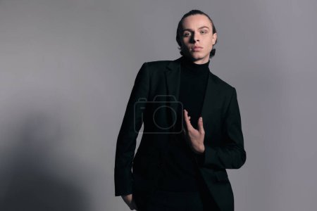 Photo for Fashion picture of sexy businessman pointing at himself with sensual moves and wearing a nice outfit against gray studio background - Royalty Free Image