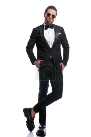 Photo for Attractive businessman posing in a sexy stance with hands in pockets and wearing glasses against white studio background - Royalty Free Image