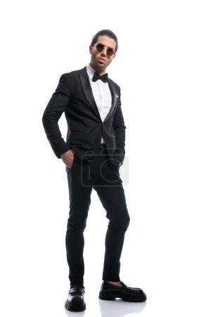 Photo for Sexy businessman posing relaxed with hands in pockets and wearing glasses against white studio background - Royalty Free Image