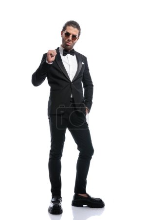 Photo for Elegant businessman pointing at himself with one hand in pocket and wearing glasses against white studio background - Royalty Free Image