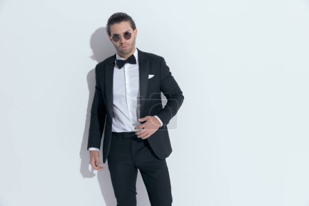Photo for Attractive businessman posing with hands hanging loosely around body, wearing glasses against white studio background - Royalty Free Image
