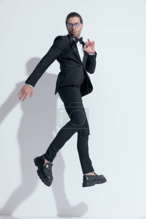 Téléchargez les photos : Homme d'affaires sexy sautant avec style dans l'air, portant des lunettes sur fond de studio blanc - en image libre de droit