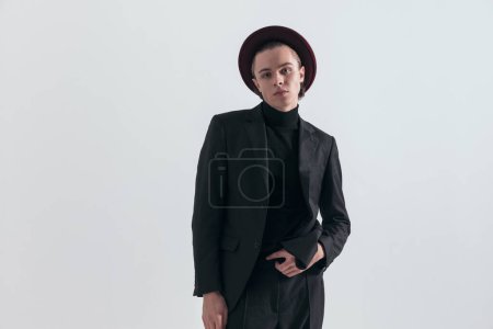 Foto de Imagen de moda de hombre de negocios guapo posando con actitud y usando un traje elegante contra fondo gris estudio - Imagen libre de derechos