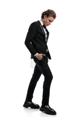 Photo for Elegant businessman walking with his head bowed , wearing a formal outfit against white studio background - Royalty Free Image